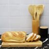 Sliced bread on wooden board with kitchen utensils