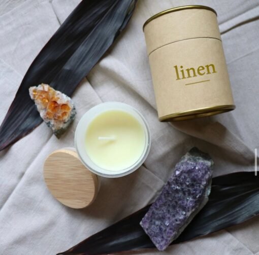 Candle in glass with wooden lid, crystals, on linen fabric