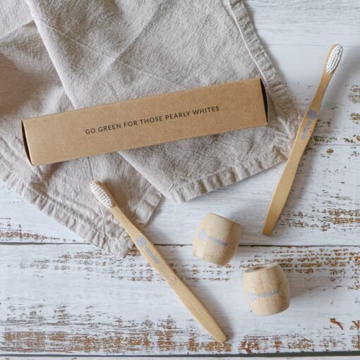 Eco-friendly bamboo toothbrushes and packaging on wooden surface